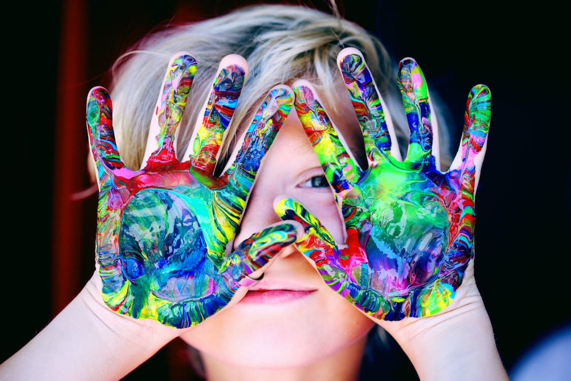 A child with messy but beautifully colorful hands